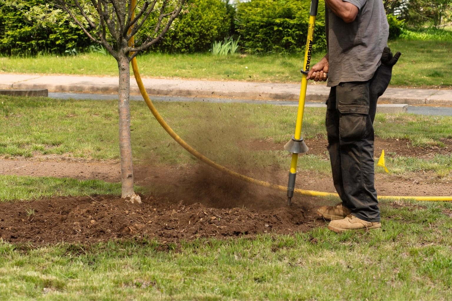 Person using an AirSpade tool to air till